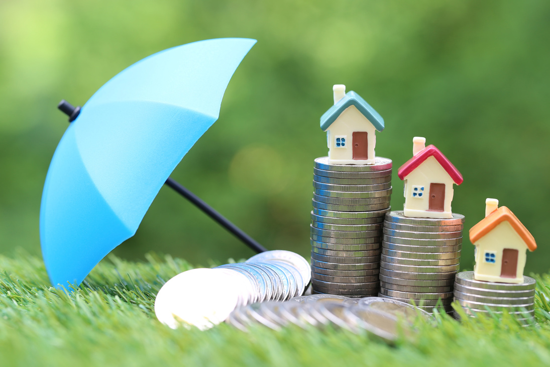 Houses on Top of Stacks of Coin beside an Umbrella 